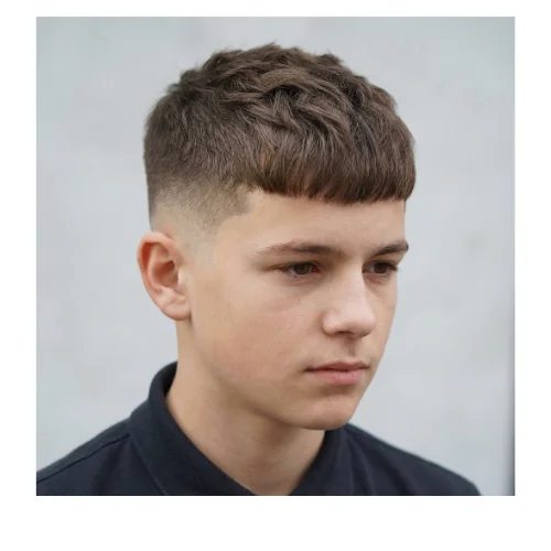 Boy with a short fringe on top and a clean low taper fade on the sides, creating a simple, neat, and school-appropriate haircut.