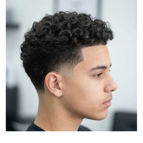 Boy with natural curly hair on top and a clean low taper fade on the sides, creating a neat and school-appropriate hairstyle.